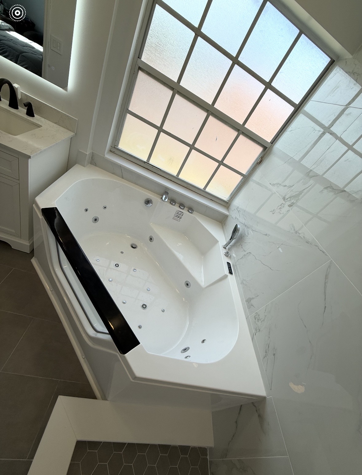 Corner jetted soaking tub with marble-look tile surround