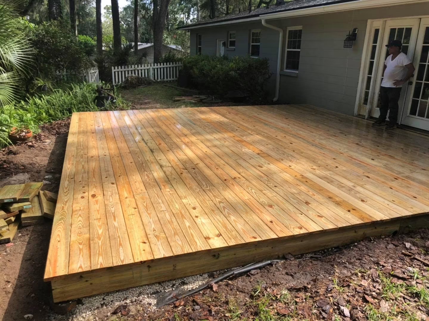 After: a finished pressure-treated deck sits flush against the back french doors, fully framed and decked