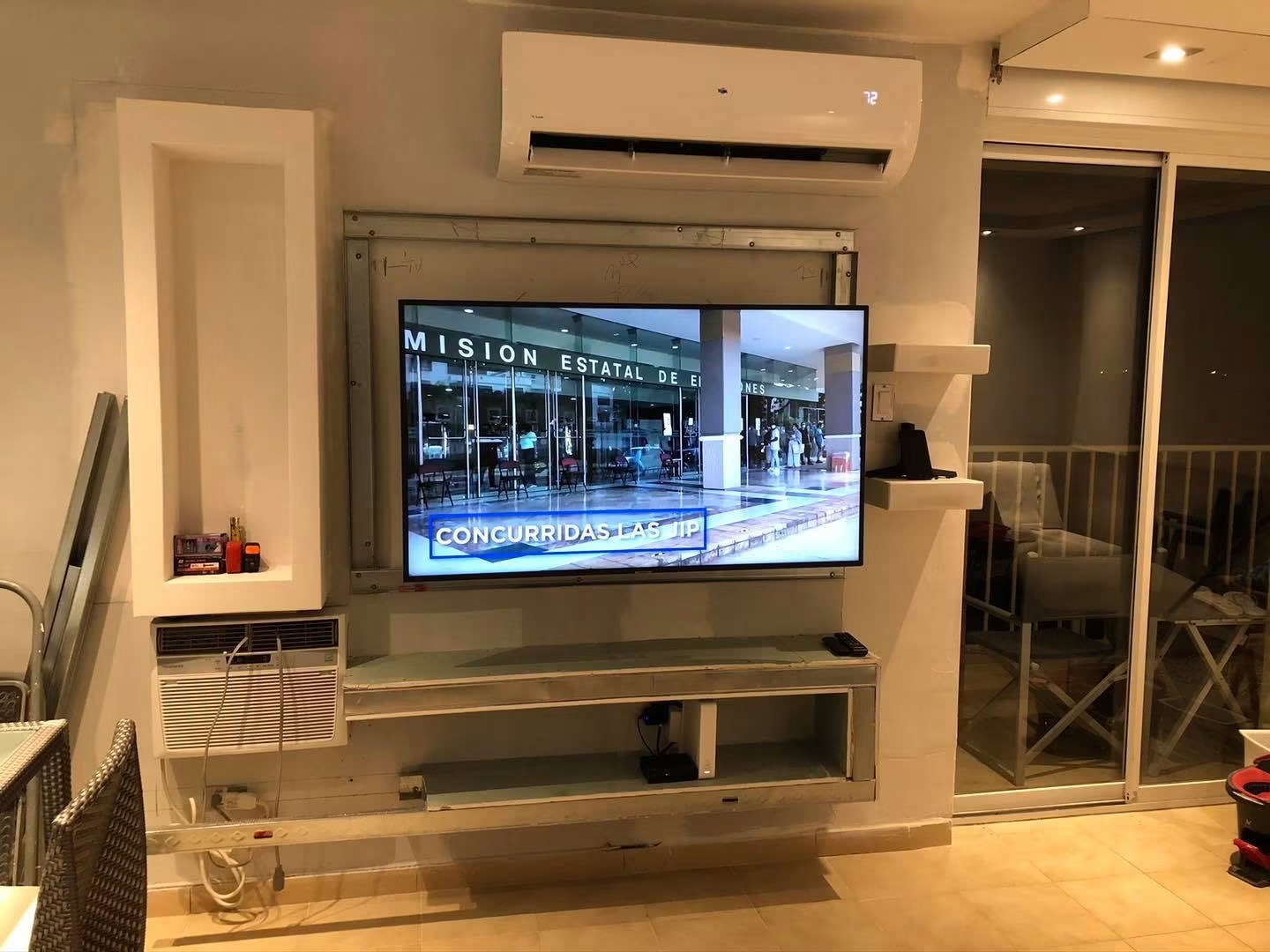 Metal-framed TV wall with the television mounted and cabinet boxes rough-framed