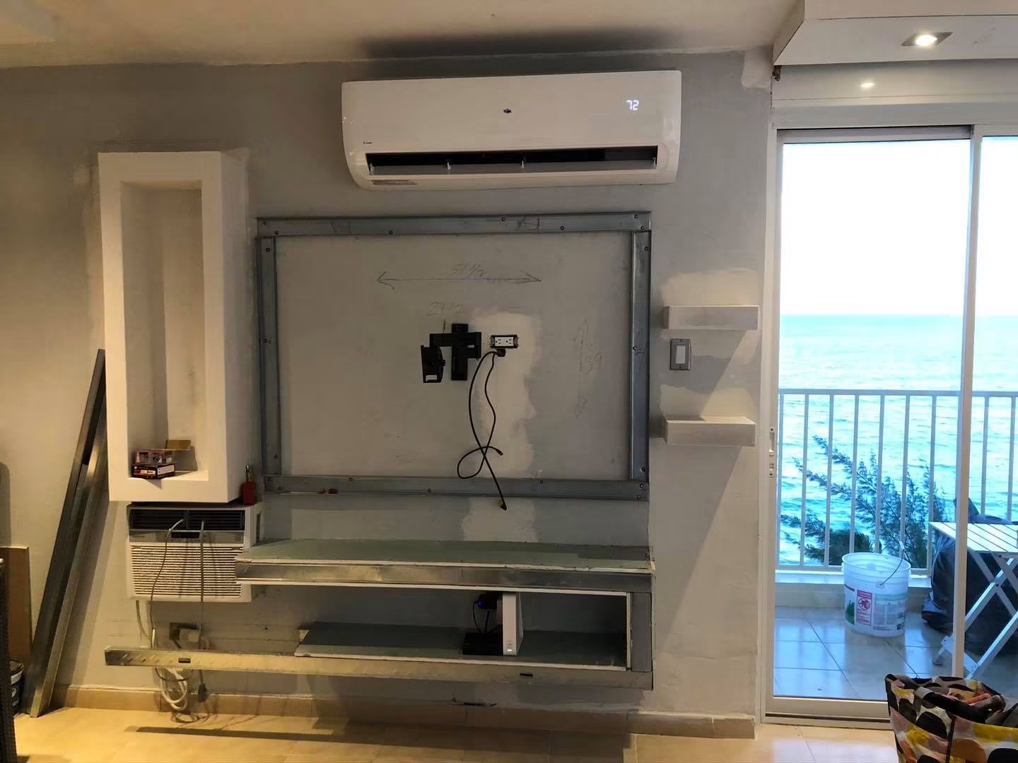 Living room wall with steel stud framing and rough openings before the media wall was finished