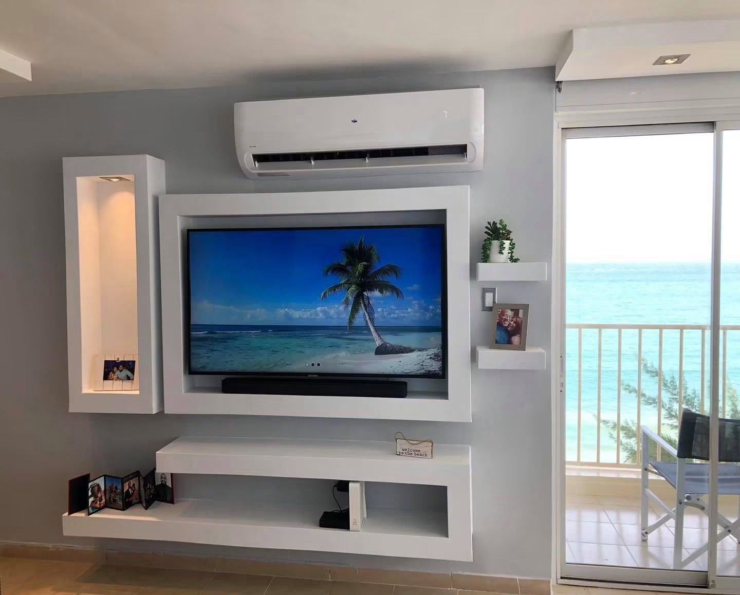 Finished white floating media wall with recessed TV and lit niche