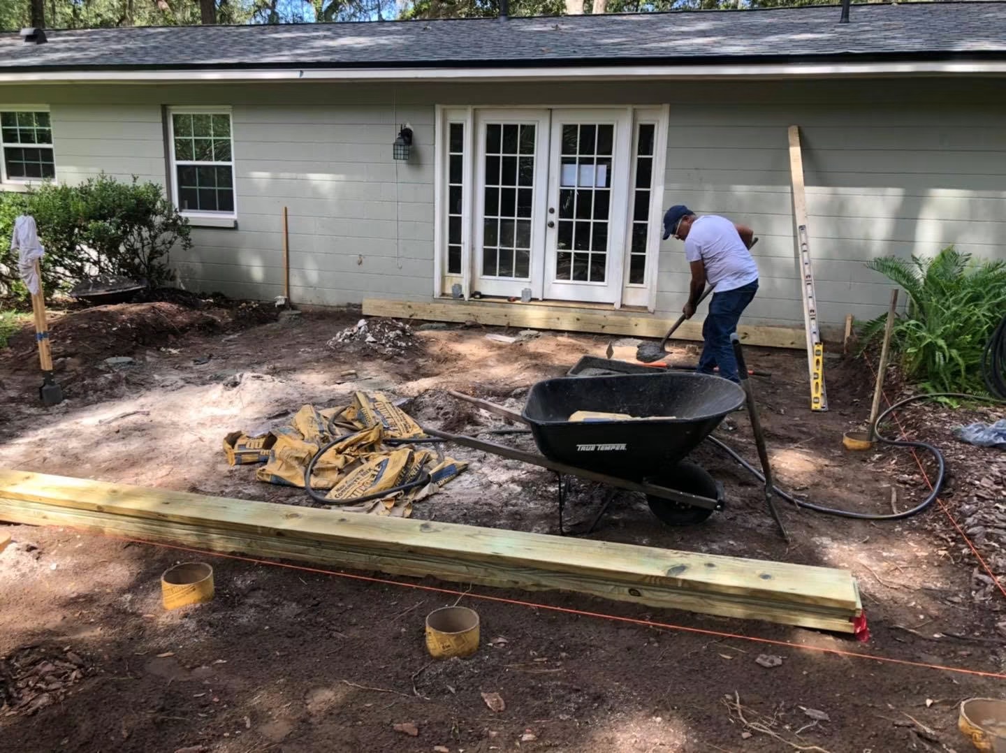 Before: the backyard was bare dirt with wooden stakes, string lines and stacked lumber — nothing built yet